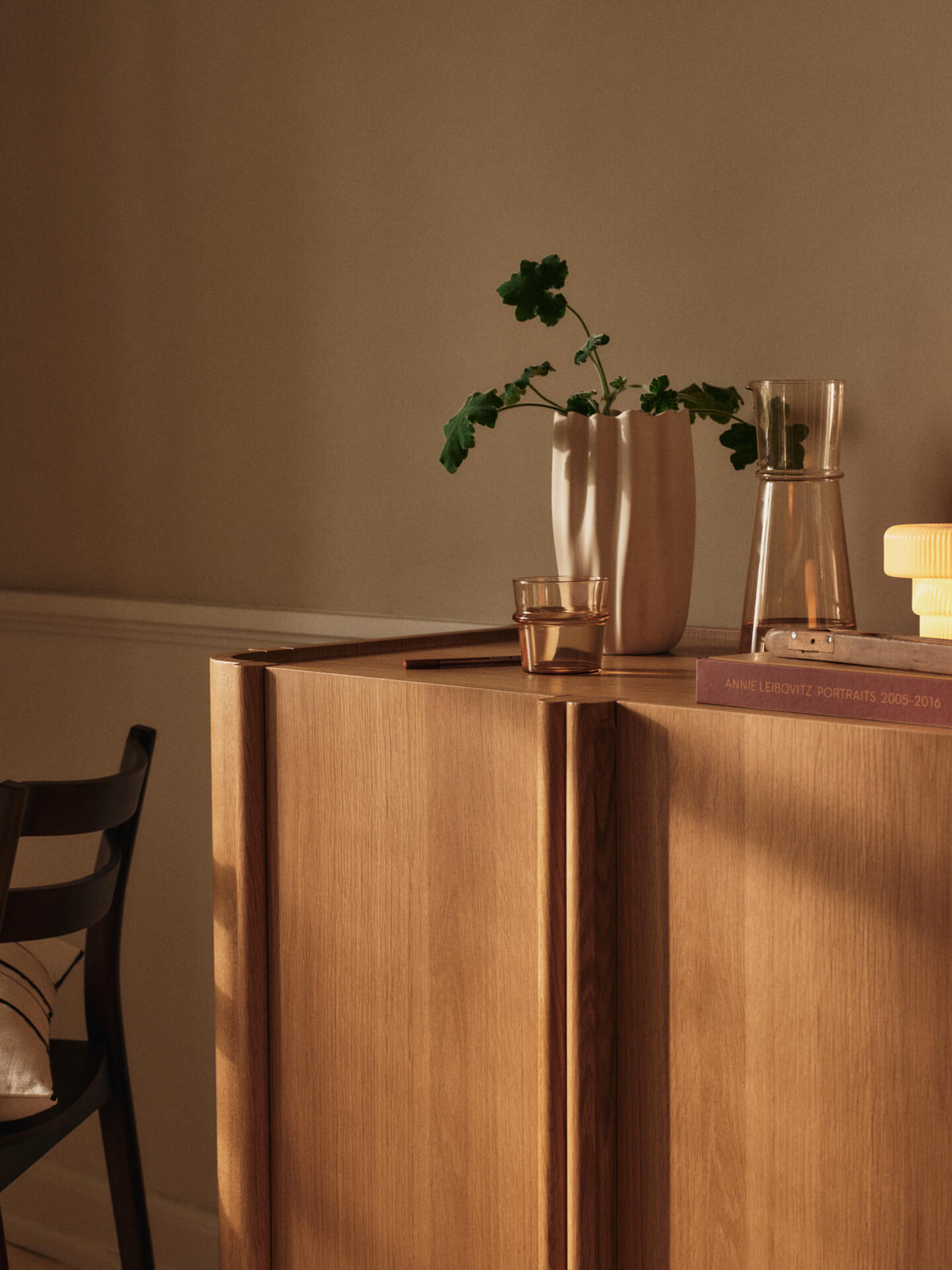 Vase Nium blanc cassé avec des branches sur un meuble en bois.
