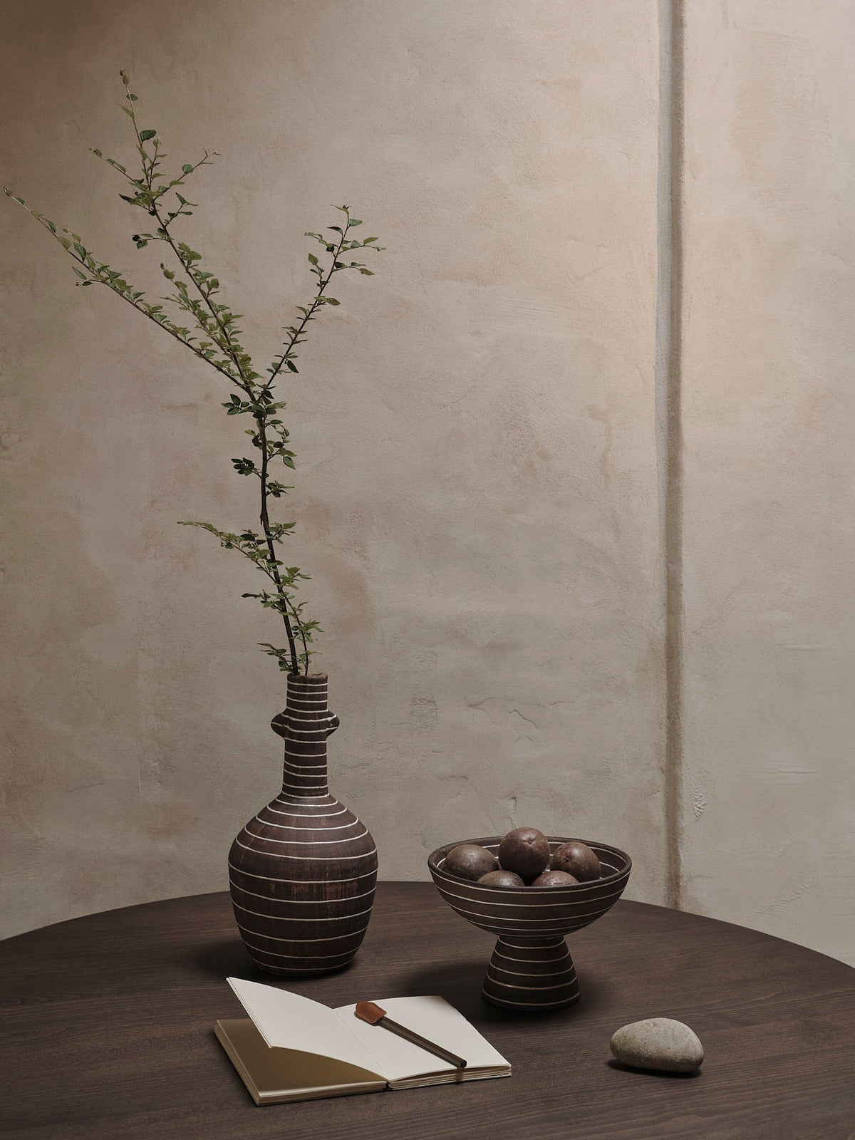 Vase Brura café et blanc avec une branche sur une table.